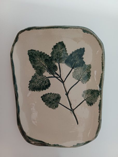 Ovaal bord met groene bladeren op een lichte achtergrond.