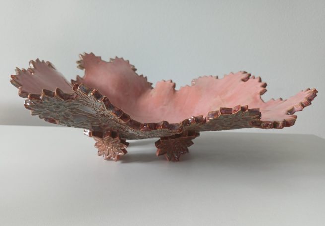 Fruitschaal. Binnenkant roze. Buitenzijde bloemmotief en ook de pootjes zijn in de vorm van een bloem