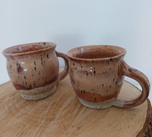Twee handgemaakte keramische kopjes met een rustieke glazuurafwerking.
