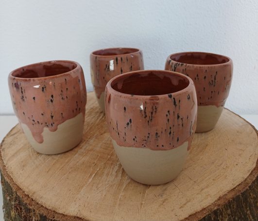 Vier keramische kopjes met een bruin-roze glazuur en een beige onderkant.