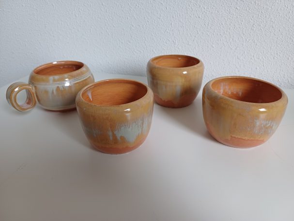 Set van vier aardewerken bekers in een warme oranje tint met een glazuurafwerking.