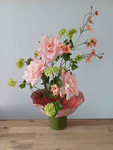 Keramische bloemenvaas met o.a zijden rozen. Het onderste deel is groen en daarboven is met een combinatie van glazuren gebruikt 