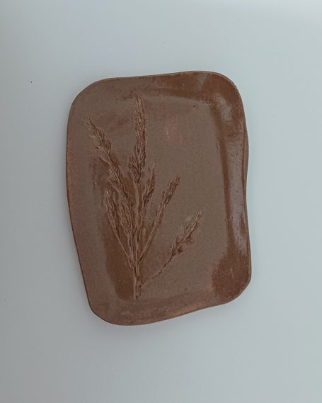 bruin keramisch schaaltje met daarin een afdruk van grassoorten