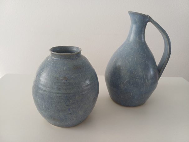 Twee blauwe keramische voorwerpen: een bolvormige pot en een ronde kruik.