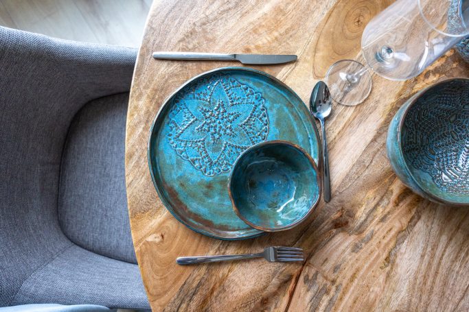Etenstafel met een blauwe, gedecoreerde schaal en bord op een houten tafel.